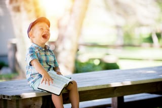A boy laughing with a book