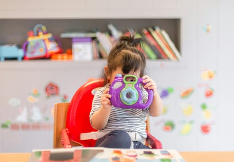 A toddler holding a toy camera