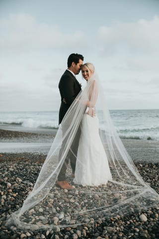 A couple on a beach with a long veil